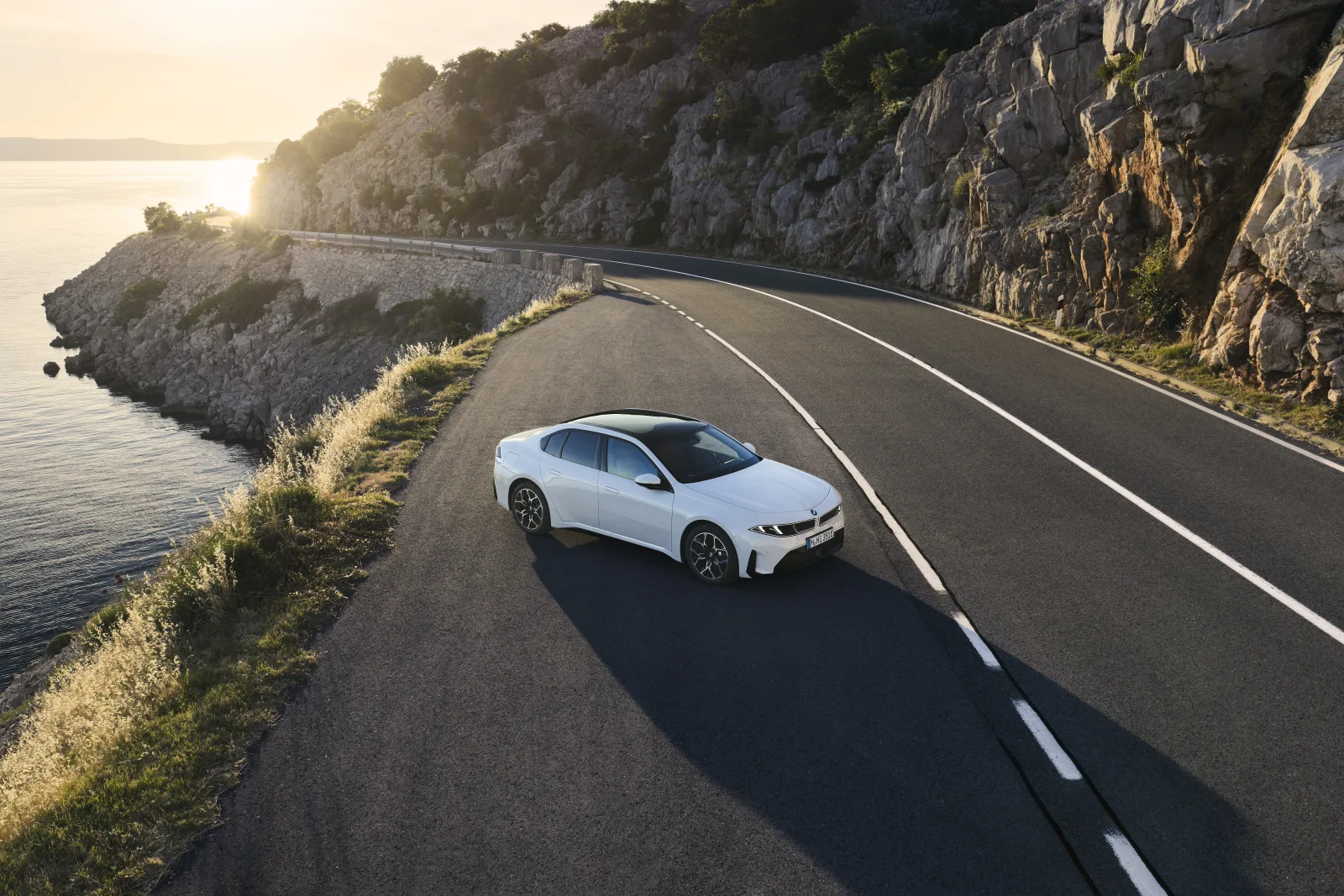 BMW i3 50 xDrive rijdend langs de kust bij zonsondergang